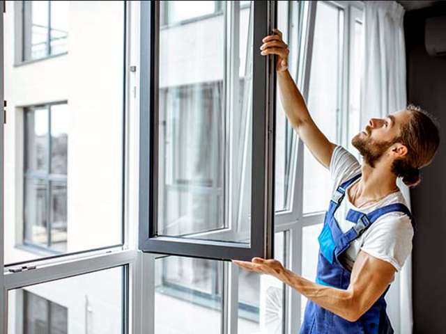 Poseur ajustant l'ouverture d'un châssis nouvellement installé